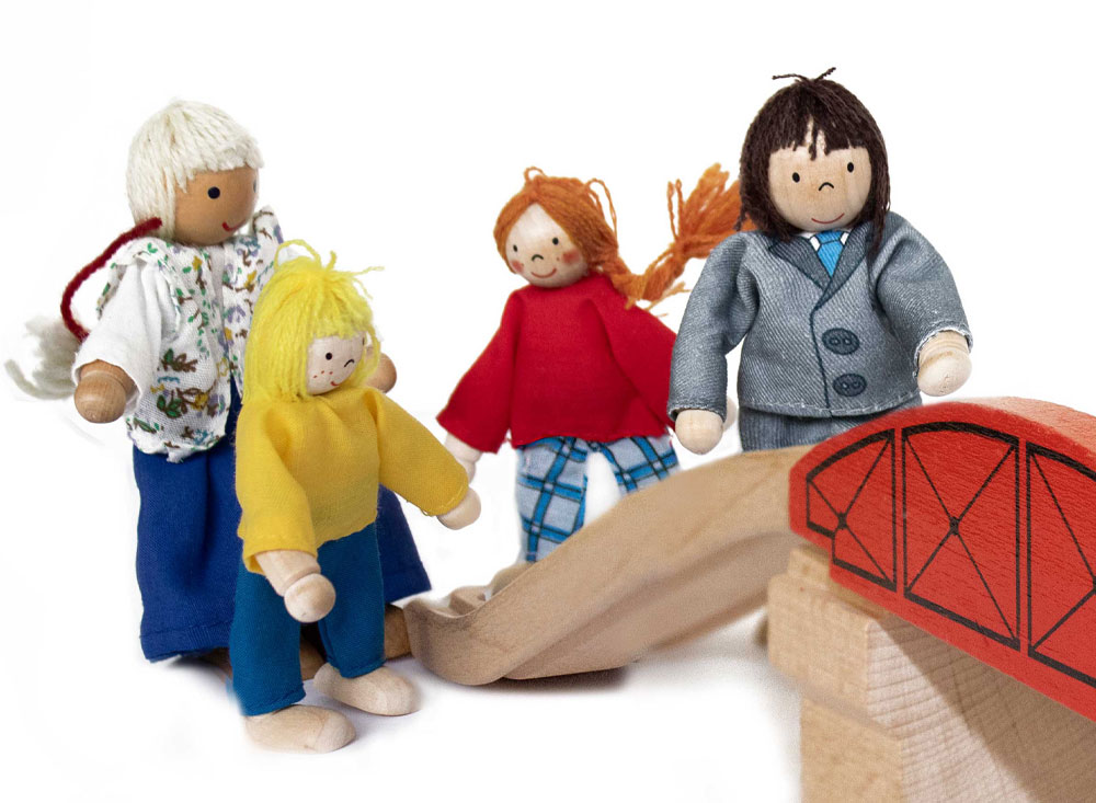 Innenansichten Koeln, Bild Jugendamt, Eine Familie aus Holzpuppen geht gemeinsam über eine Spielzeug Holzbrücke 